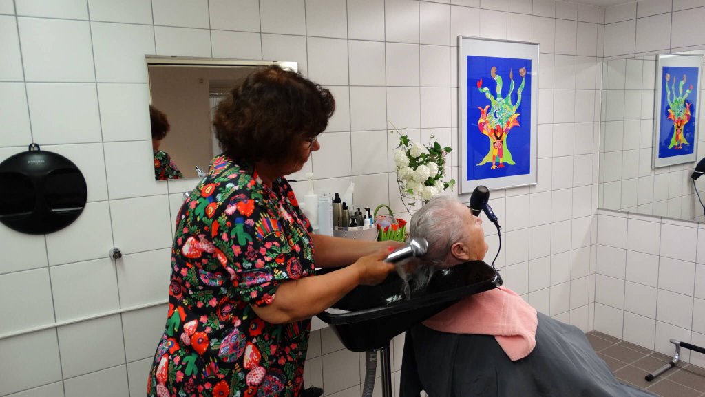 La coiffeuse essuie les cheveux d'une habitante de Mon Repos.